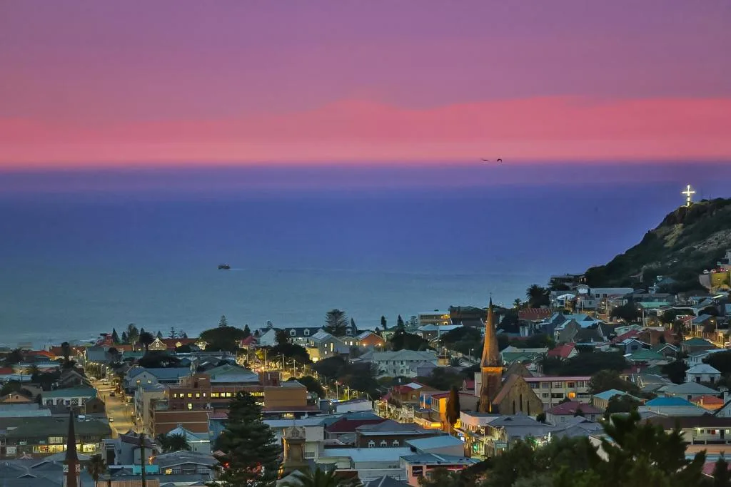 Sunset over Mossel Bay town with ocean and coastal buildings glowing