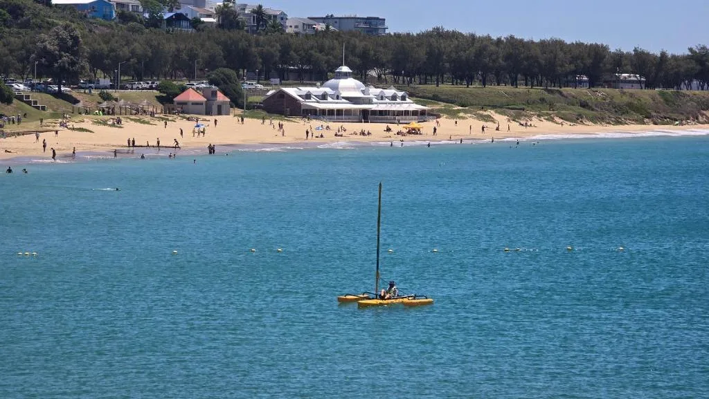 Turquoise ocean with sandy beach and beachfront buildings visible