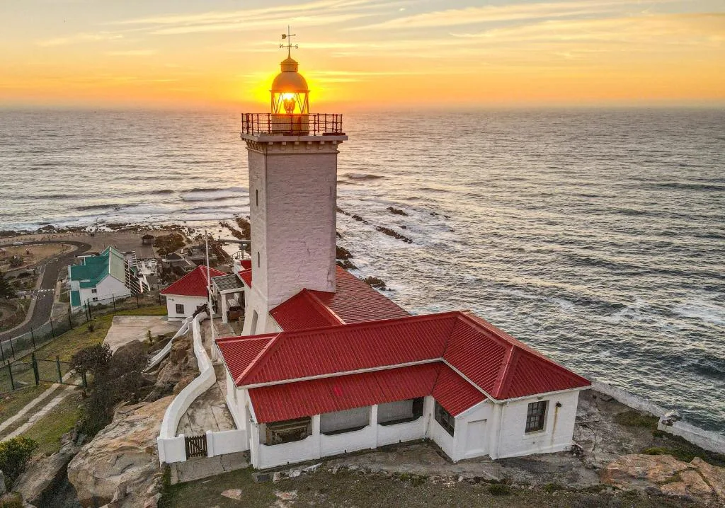 Iconic lighthouse at sunset overlooking the Atlantic Ocean and coastal cliffs