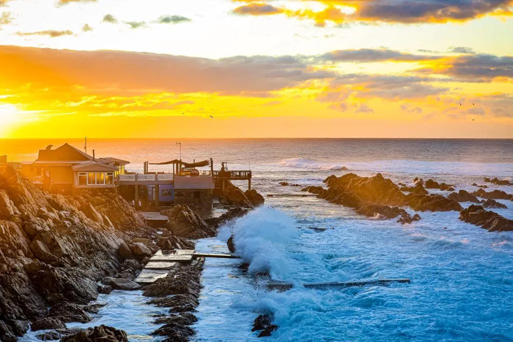 Sunset over ocean with rocky coastline and beachfront property