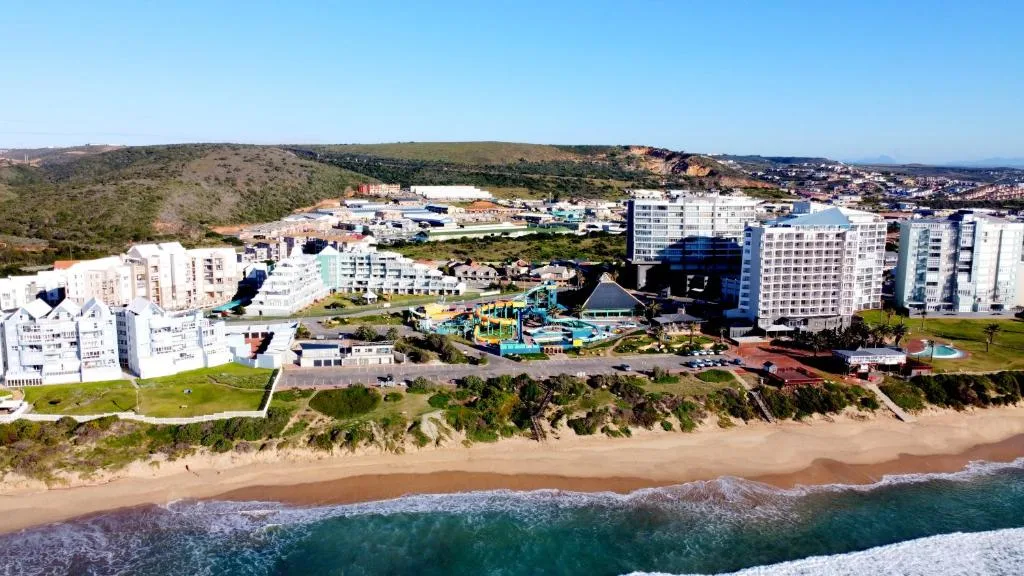 Aerial view of beachfront resort with ocean, beach, and surrounding town