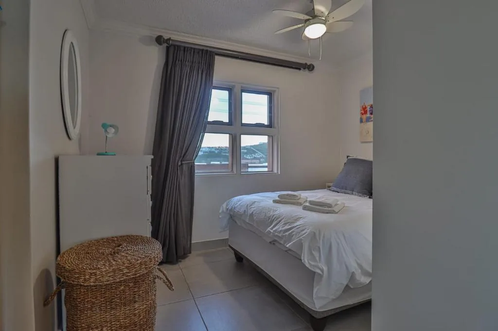 Bright bedroom with double bed, window view of lagoon, ceiling fan