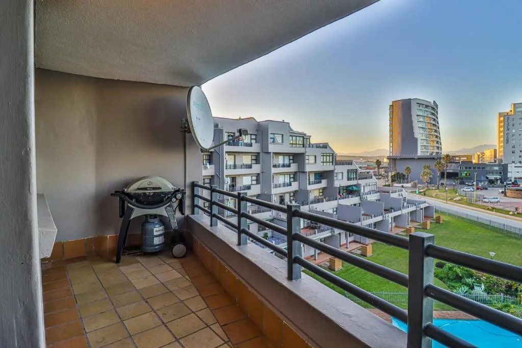 Covered balcony with braai grill overlooking modern apartment complex and town