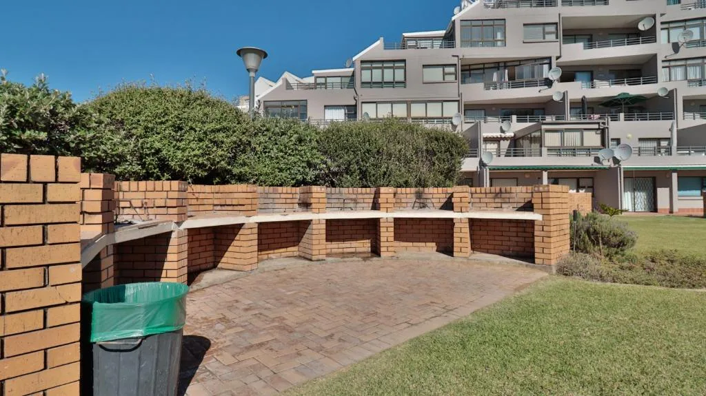 Brick braai area with benches overlooking manicured lawn and garden