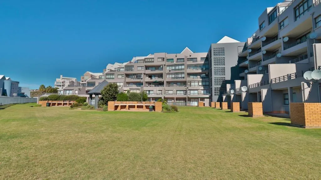 Modern apartment building complex with manicured lawn and clear blue sky