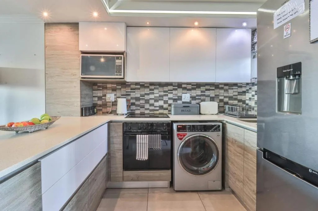 Modern kitchen with white cabinetry, geometric backsplash, and stainless steel appliances