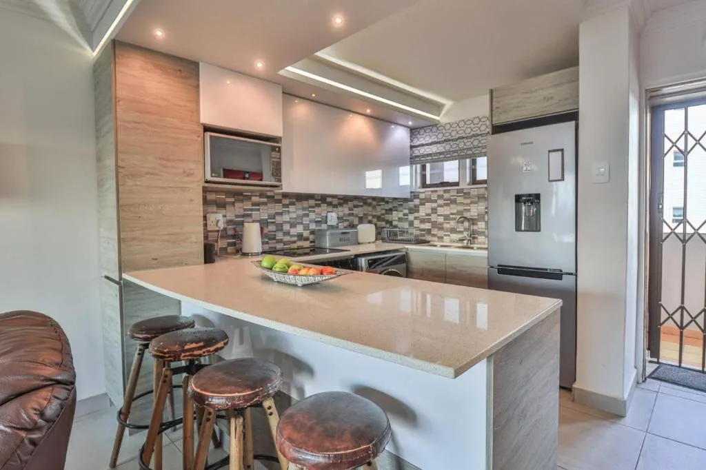 Modern kitchen with island counter, bar seating, and tiled backsplash