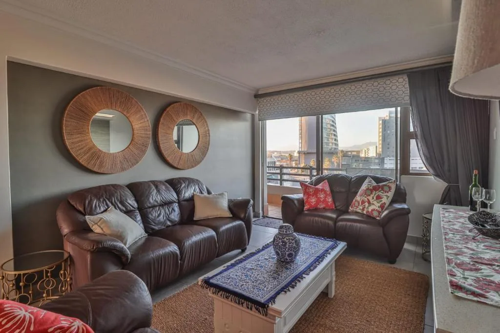 Modern lounge with brown leather sofas, decorative mirrors, and city views