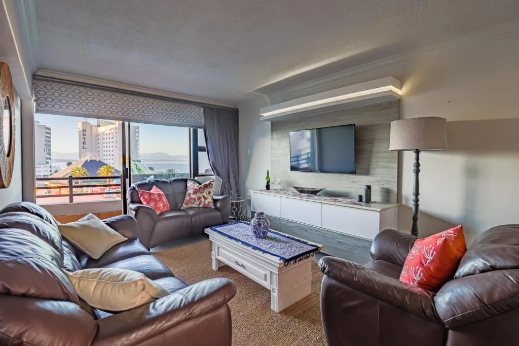 Spacious lounge with leather sofas, TV wall, and panoramic ocean views