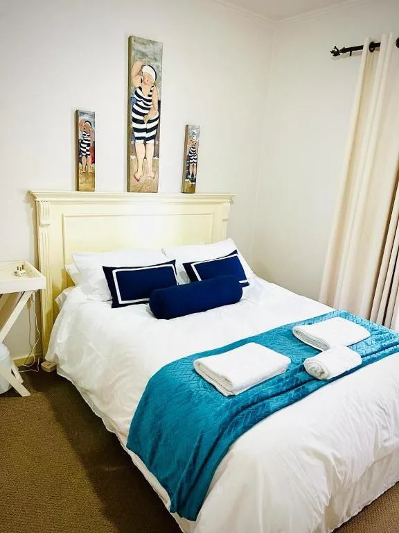 Bright bedroom with cream headboard, white bedding, blue pillows and throw
