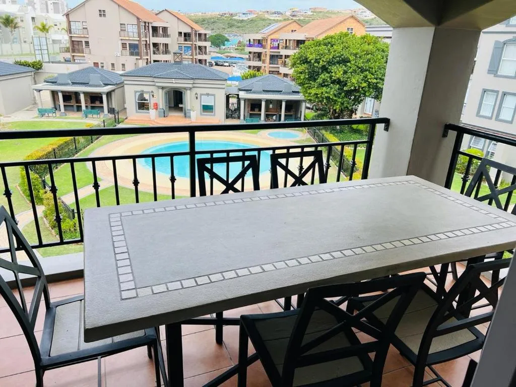 Elevated balcony with dining table overlooking pool and gardens