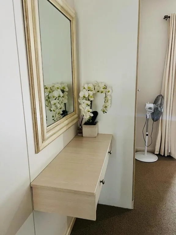 Wooden vanity with mirror, white orchids, and decorative accessories