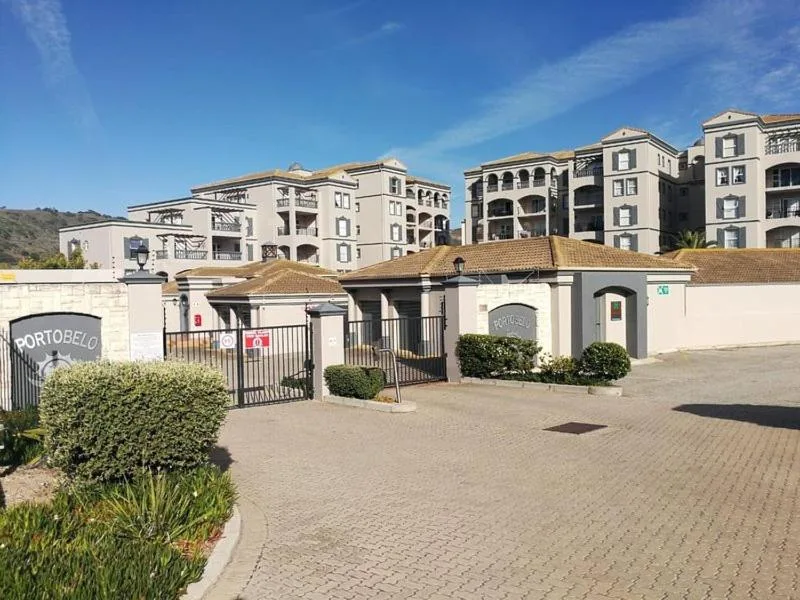 Gated apartment complex entrance with manicured landscaping and hills