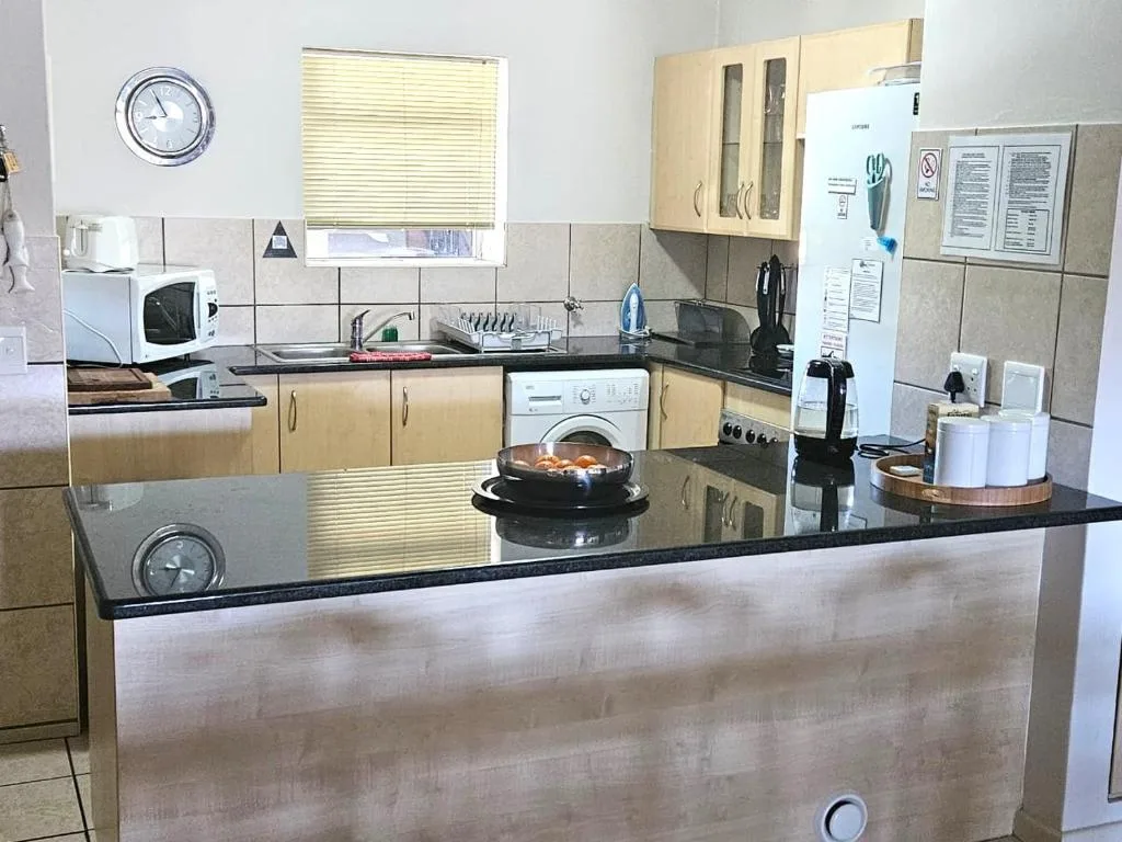 Spacious kitchen with black countertops, light wood cabinets, and modern appliances