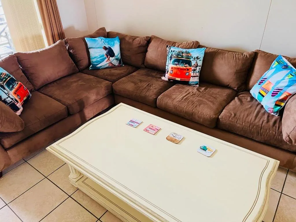 Brown sectional sofa with colorful throw pillows and cream coffee table