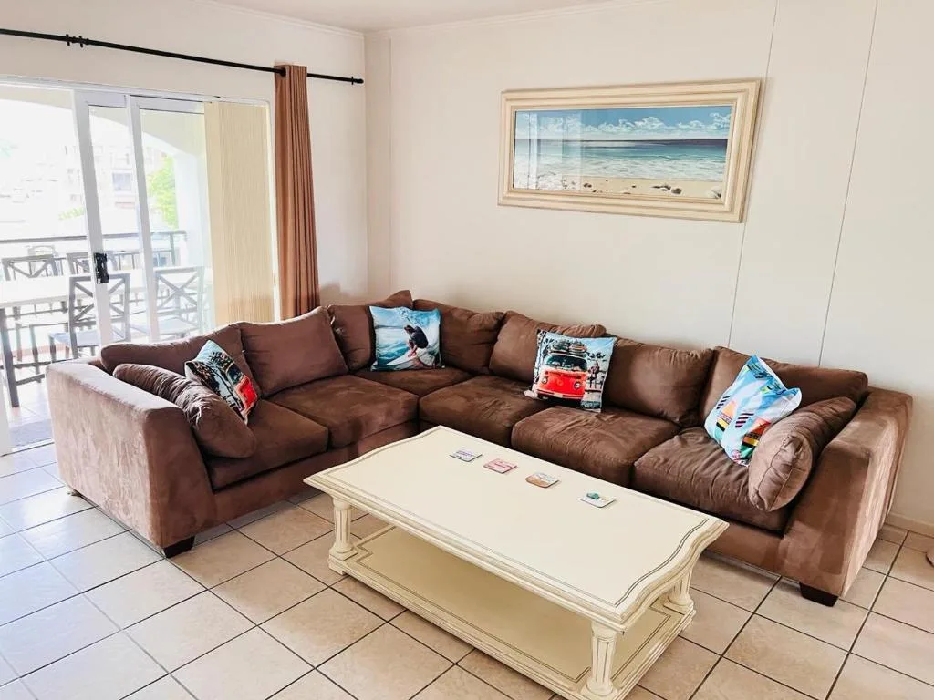 Spacious lounge with brown sectional sofa and cream coffee table overlooking deck