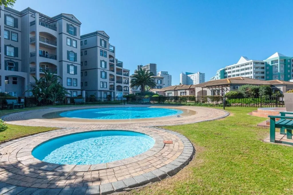 Two circular swimming pools with vibrant blue water in manicured lawn area