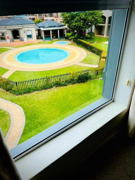 Aerial view of circular swimming pool and manicured gardens from window
