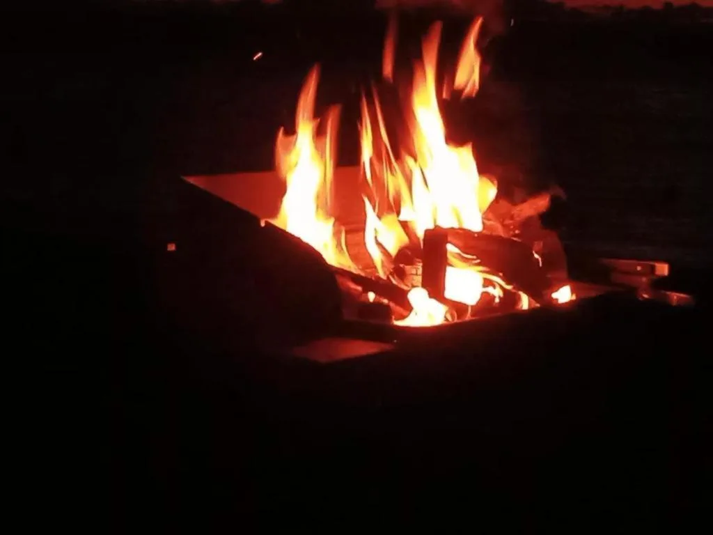Glowing fire pit with bright flames on outdoor patio at night