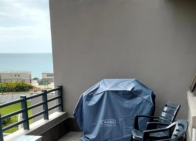 Covered balcony with ocean view, grill, and seating area