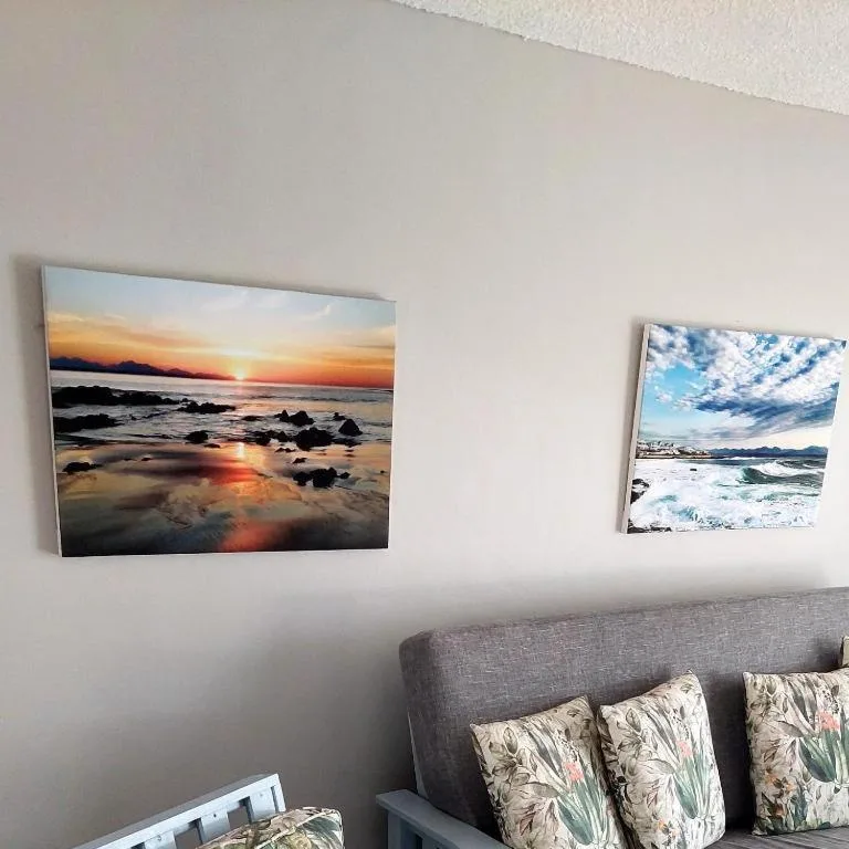 Coastal sunset and ocean wave canvas prints above gray sofa