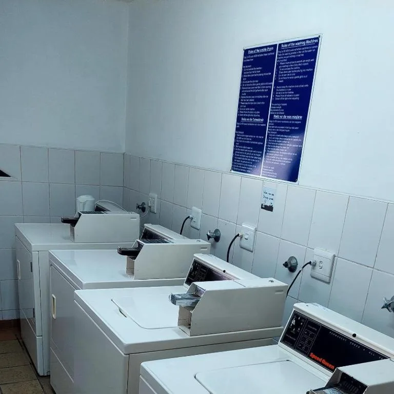 Shared laundry room with multiple white washing machines and instructional posters
