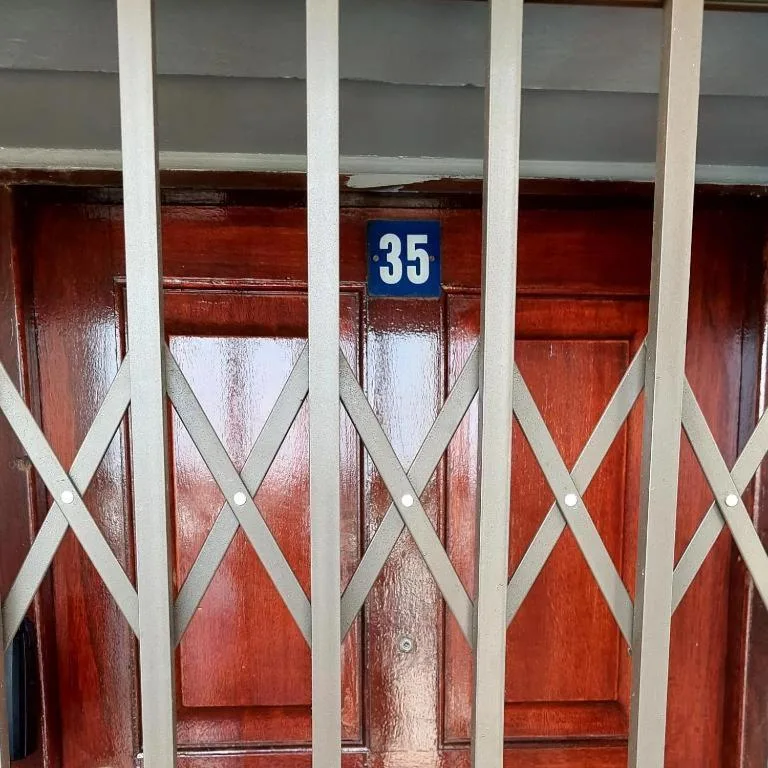 Red wooden door with white security grille and blue number thirty-five