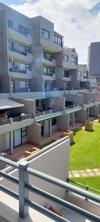 Modern multi-story apartment building with balconies and manicured lawn grounds