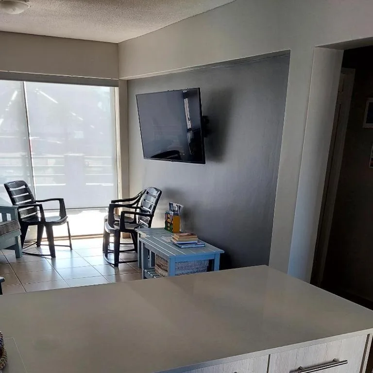 Modern lounge with wall-mounted TV, comfortable seating, and ocean view access