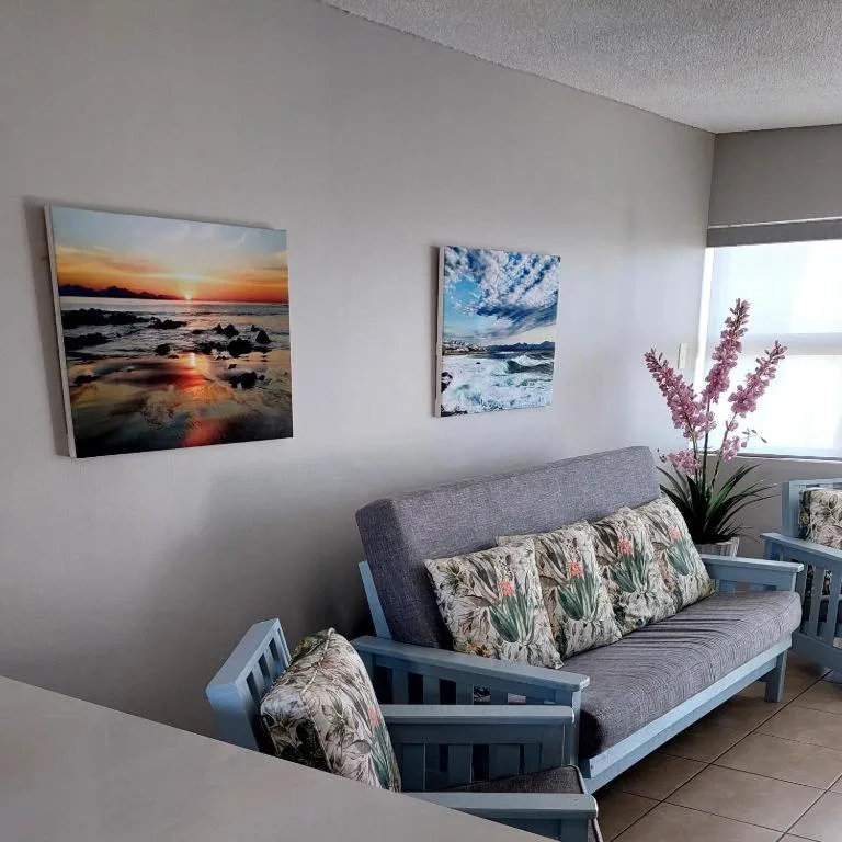 Bright lounge with gray sofa, floral cushions, and coastal artwork on walls