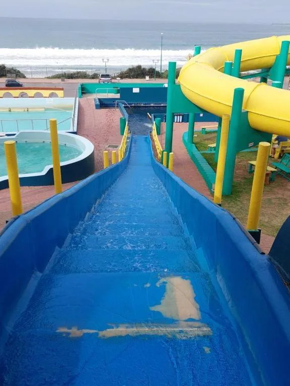 Water slide with yellow spiral tube and ocean view beyond