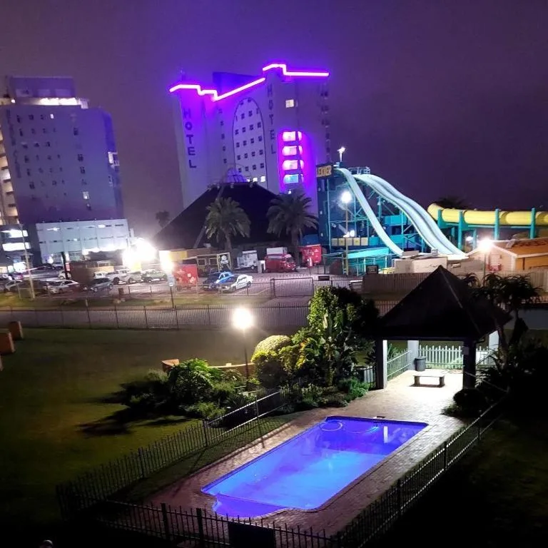 Illuminated swimming pool overlooking vibrant Mossel Bay beachfront at night