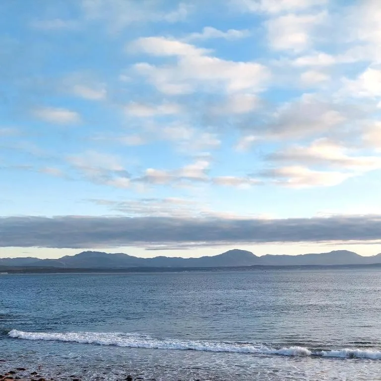 Scenic ocean and mountain vista with blue sky and clouds