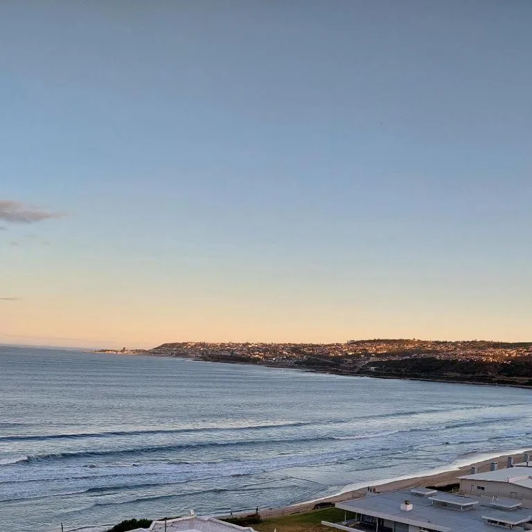 Scenic coastal view with beach, ocean waves, and seaside town at dusk