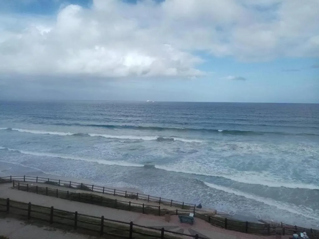 Ocean waves and beach with distant horizon from elevated vantage point