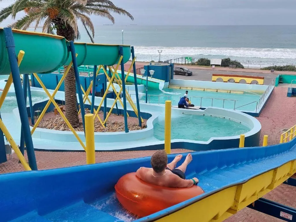 Beach and ocean view from poolside with colorful water park facilities