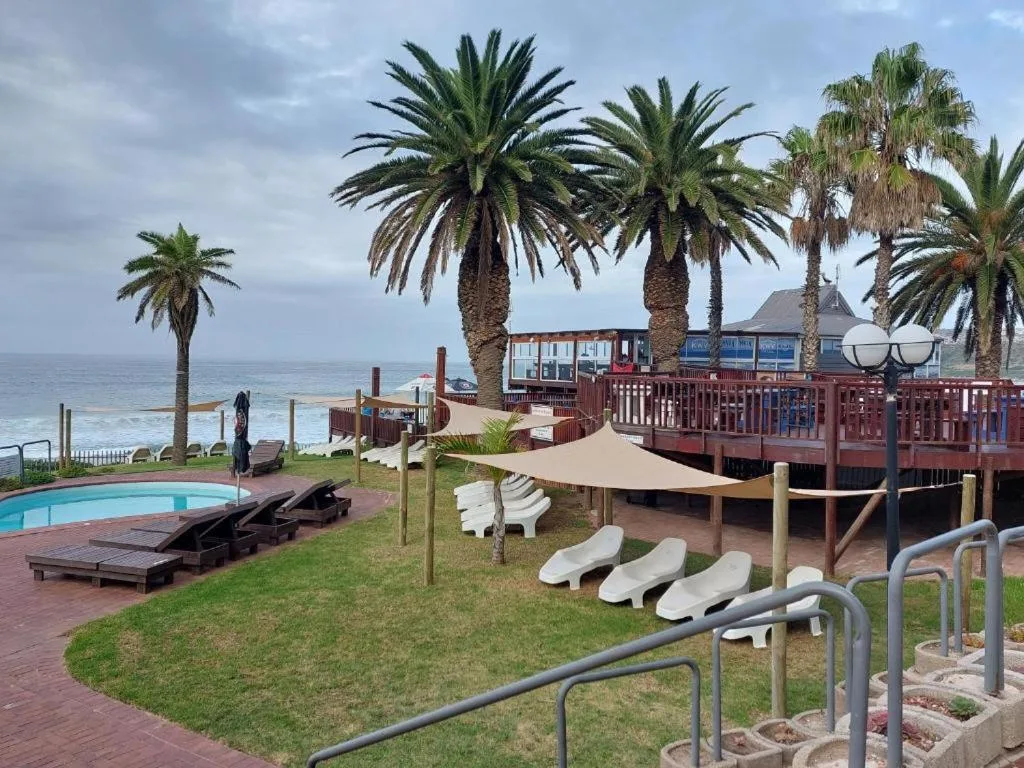 Oceanfront property with palm trees, pool, and beachside deck overlooking sea