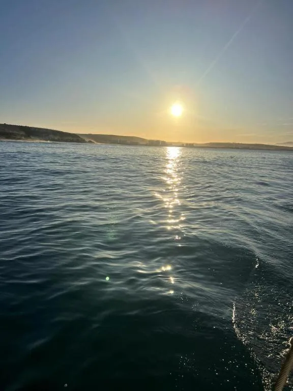 Golden sunrise over calm ocean waters with coastal cliffs beyond