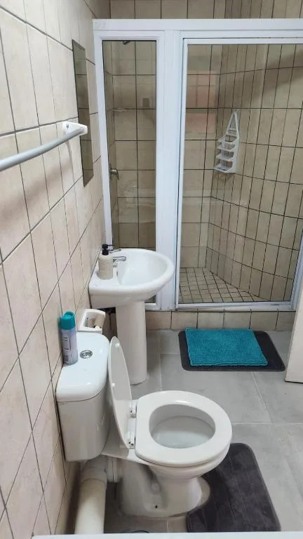 Clean bathroom with toilet, pedestal sink, and enclosed shower cubicle