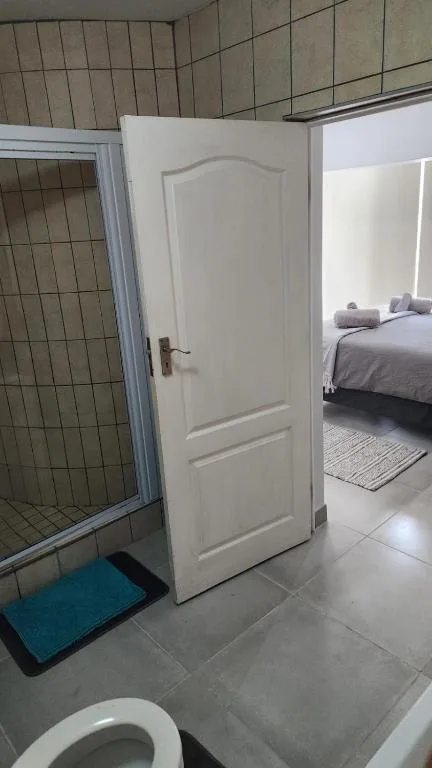 Bathroom with shower cubicle, toilet, and open door to bedroom