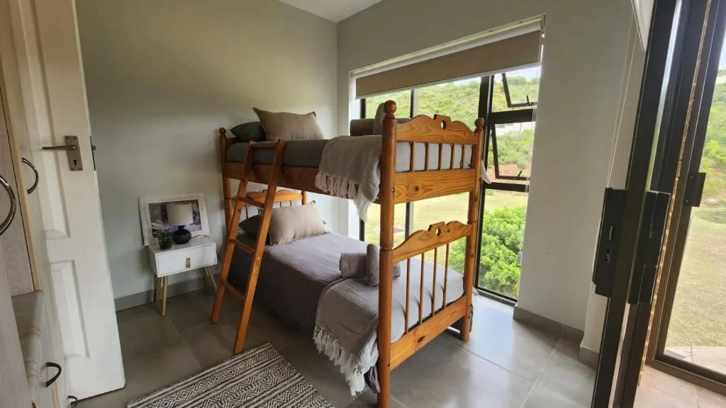 Bright bedroom with wooden bunk beds and scenic green views through large windows