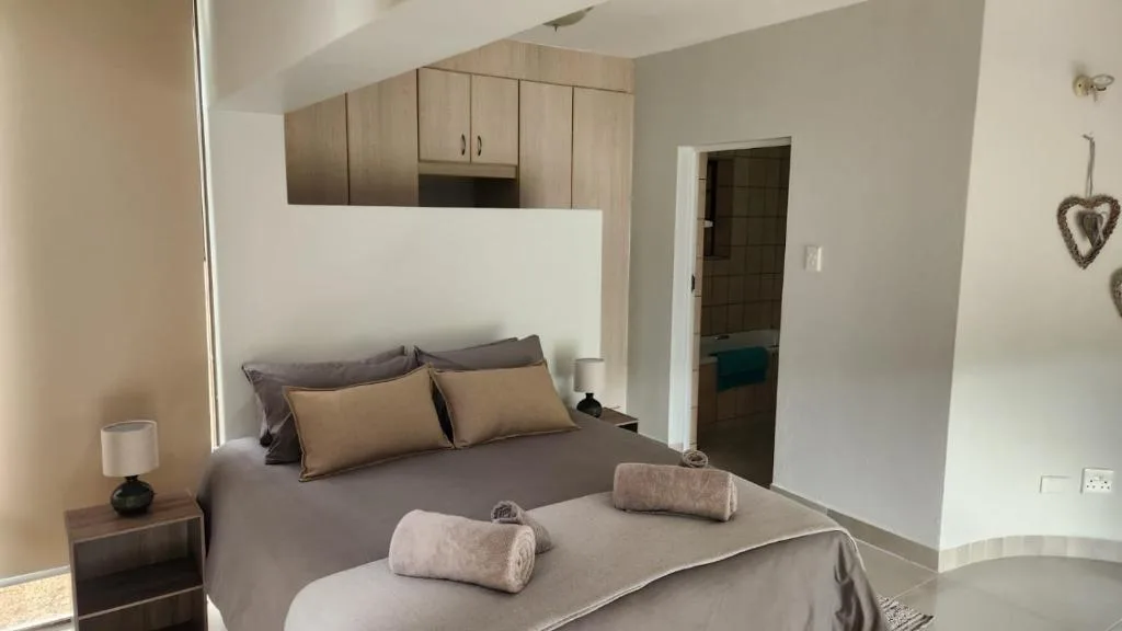 Modern bedroom with double bed, neutral linens, and wooden cabinetry
