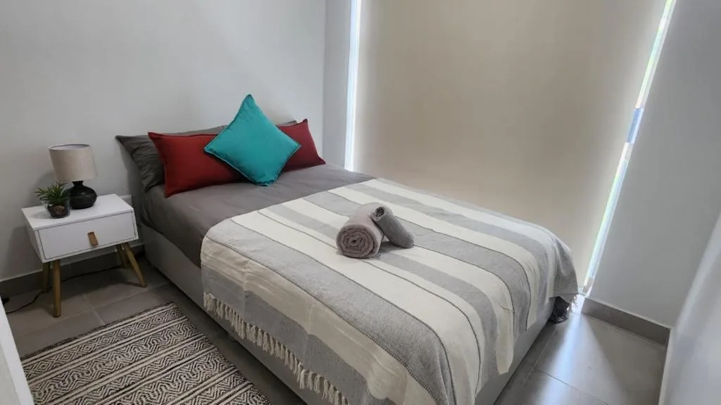 Modern bedroom with grey and white striped bedding and colorful accent pillows