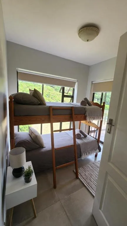 Bright bedroom with wooden bunk beds and large windows overlooking greenery