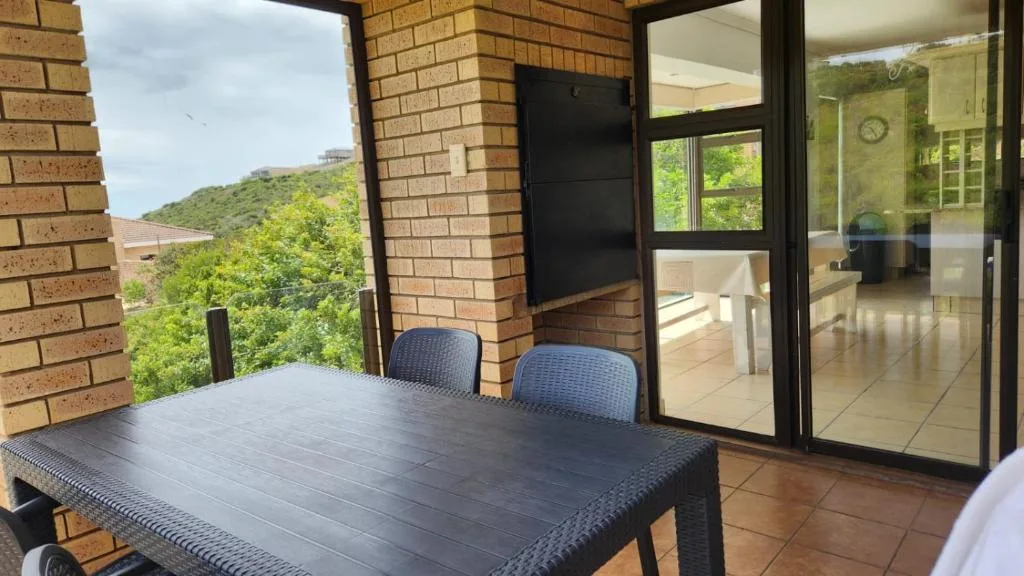 Outdoor patio with dining table, chairs, and hillside views beyond