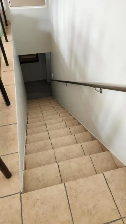 Narrow tiled hallway with handrail and white walls