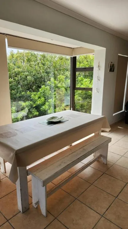 Dining table with bench seating overlooking lush green trees and vegetation