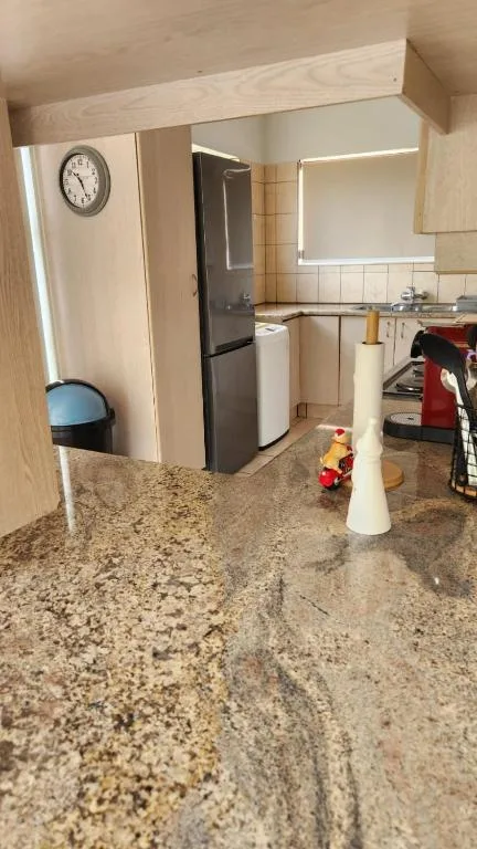 Modern kitchen with granite countertop, refrigerator, stove, and wall clock