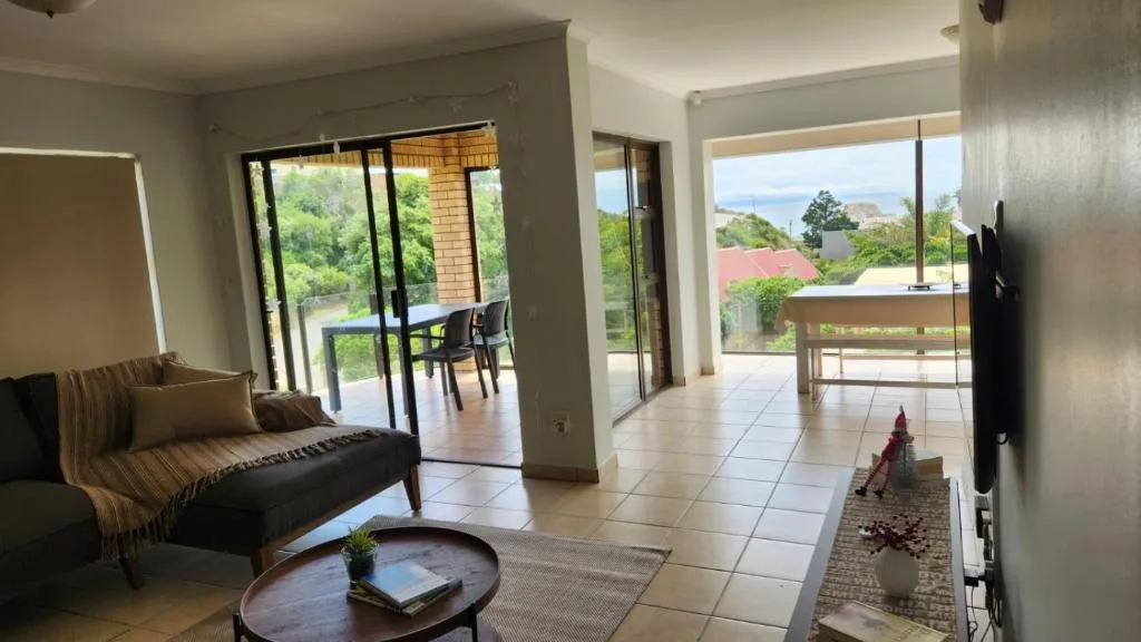 Spacious lounge with sofa, coffee table, and ocean views through glass doors
