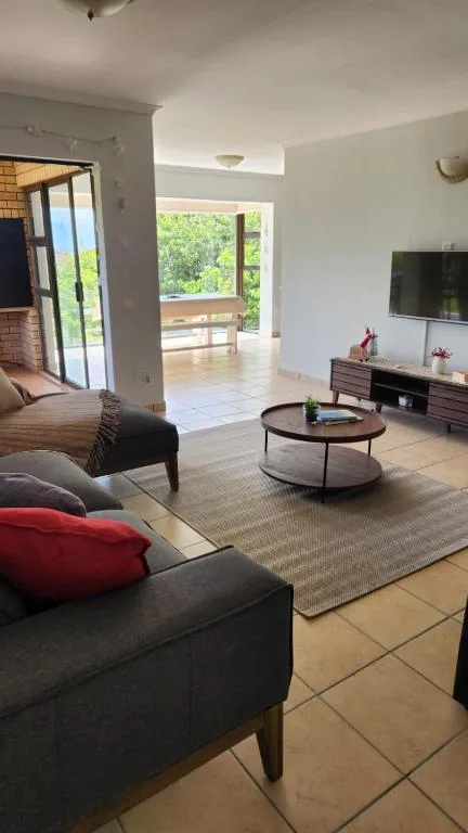 Spacious lounge with gray sofa, TV, and ocean views through glass doors